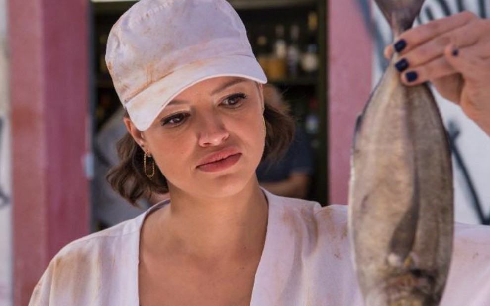 A atriz Agatha Moreira caracterizada como a Josiane de A Dona do Pedaço, segurando um peixe