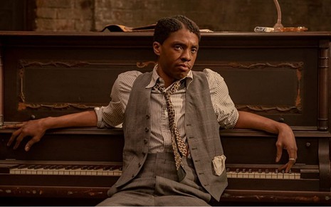 Chadwick Boseman sentado em frente a um piano em cena do filme A Voz Suprema do Blues (2020)