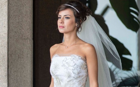 A atriz Andréia Horta está vestida de noiva e com uma expressão séria em cena como Maria Clara em Império