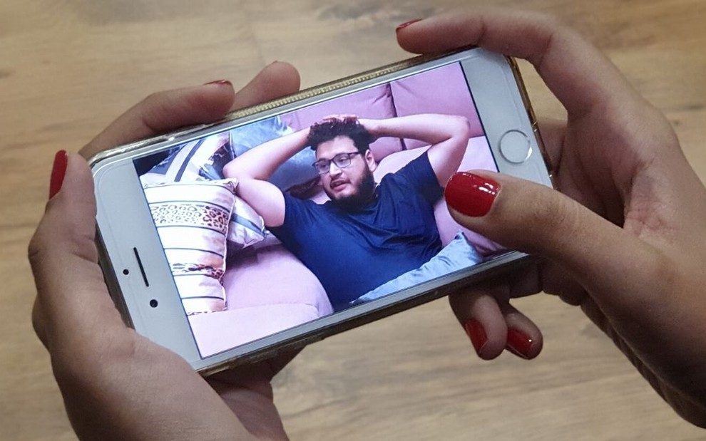 Imagem de um celular nas mãos de uma assinante do Globoplay, que está exibindo o BBB20 ao vivo pelo celular