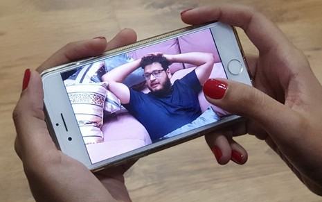 Imagem de um celular nas mãos de uma assinante do Globoplay, que está exibindo o BBB20 ao vivo pelo celular