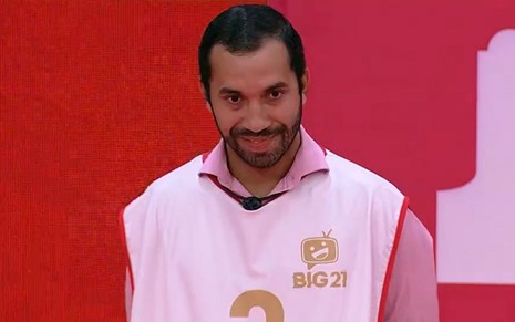 Gilberto olha para frente, usa colete branco e camiseta rosa