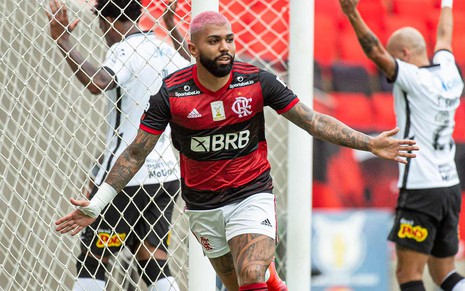 Gabigol, de cabelo rosa e braços abertos comemorando o gol que fez pelo Flamengo