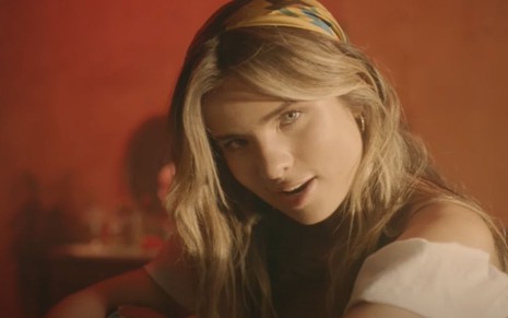 Imagem de Giulia Be, em fundo vermelho, no clipe da música Chiquita Suelta