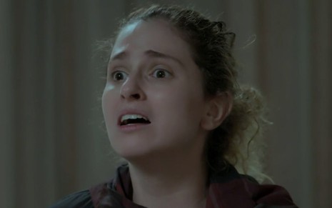 Carol Duarte caracterizada como Ivana em A Força do Querer: personagem está de cabelo preso e tem olhar desesperado para alguém fora do quadro