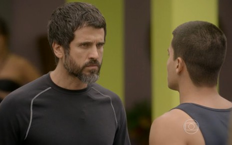 Eriberto Leão grava de camiseta de manga longa preta e expressão brava conversando com Arthur Aguiar, de costas na foto