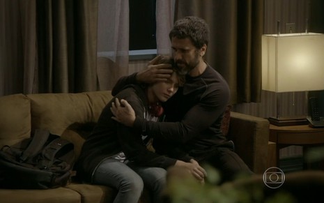 Isabella Santoni grava sentada em sofá com expressão triste; atriz está abraçada a Eriberto Leão, seu pai em Malhação