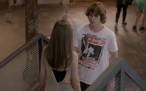 Rafael Vitti grava com camiseta estampada ao lado de Bruna Hamú, de costas na foto como Pedro e Bianca de Malhação