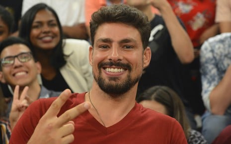O ator Cauã Reymond usa camiseta vermelha e faz sinal de "V" com os dedos durante participação no programa Altas Horas, da TV Hlobo