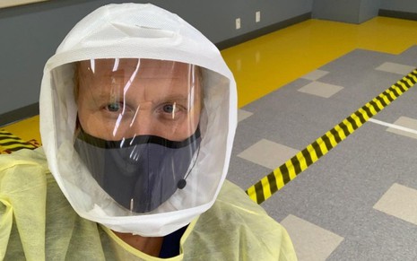 Com uma máscara no rosto, microfone e uma capa protetora, Kevin McKidd aparece todo protegido nos bastidores de Grey's Anatomy