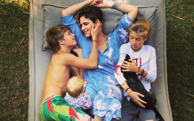 Foto da atriz deitada em uma rede com os filhos Maria, Francisco e João
