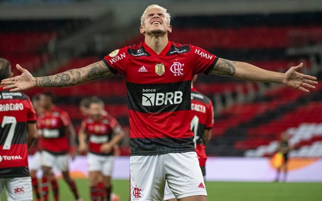Pedro com a camisa vermelha e preta e calção branco do Flamengo com cabeça virada para cima e braços abertos