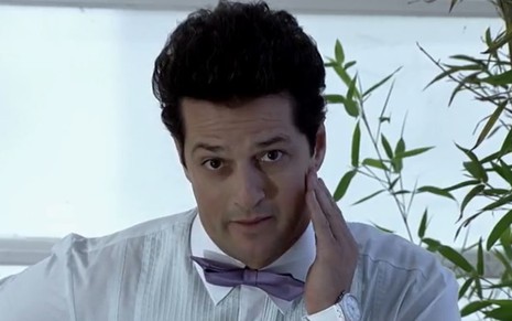 Imagem de Marcelo Serrado como Crô na novela Fina Estampa, com a mão no rosto e vestindo blusa social com gravata borboleta