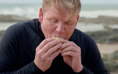 O chef de cozinha Gordon Ramsay comendo um sanduíche no programa Sabores Extremos, do canal NatGeo