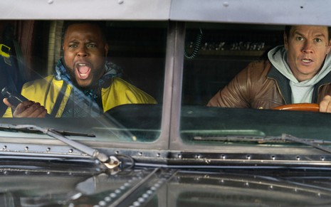 Os atores Winston Duke e Mark Wahlberg dentro de caminhão em cena do filme Troco em Dobro, da Netflix