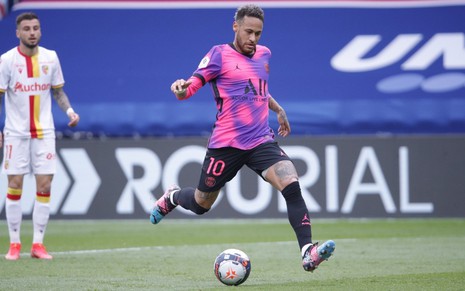 Neymar em jogo do PSG; ele está com camisa roxa e rosa do clube pronto para chutar a bola