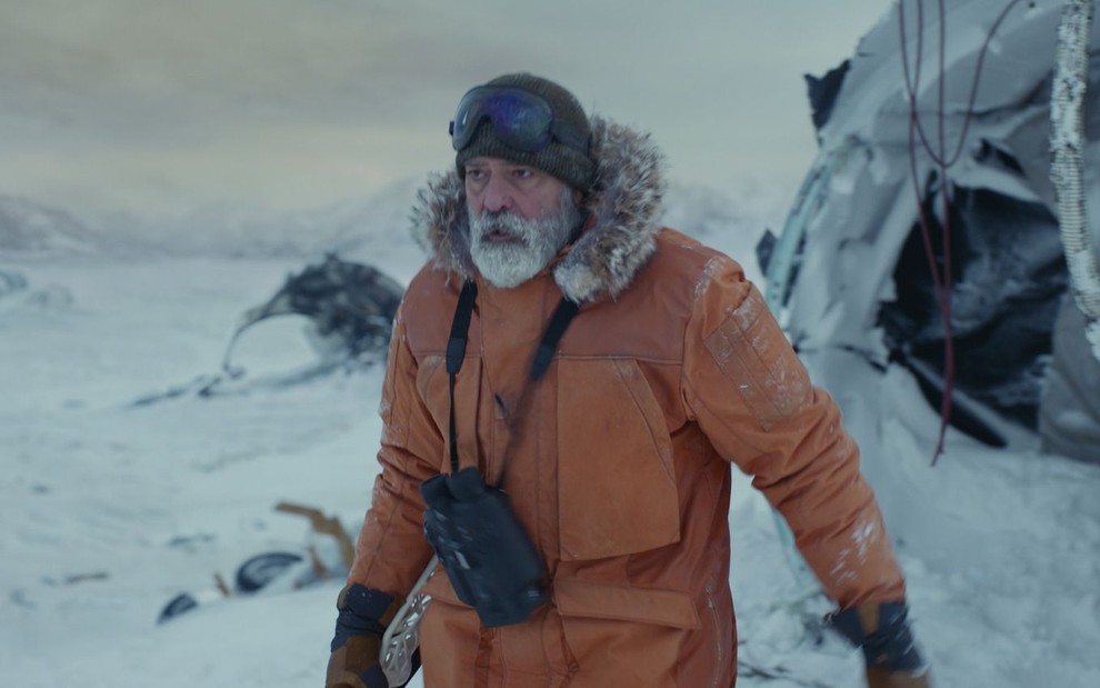 Com roupas de frio, George Clooney anda em um ambiente com muita neve em cena de O Céu da Meia-Noite (2020)