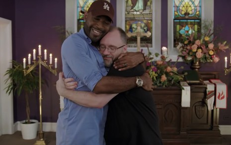 Um dos apresentadores do Queer Eye, Karamo Brown, abraça padre em igreja, em episódio do reality