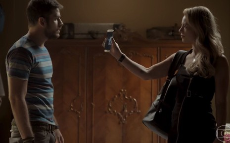 Jeiza (Paolla Oliveira) mostra uma foto no celular para Zeca (Marco Pigossi) em A Força do Querer