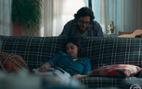 Roney (Lucio Mauro Filho) observa Keyla (Gabriela Medvedovski) exausta dormindo no sofá em cena de Malhação