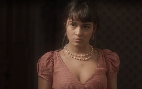 Jacira (Giullia Buscacio) com vestido e colar de pedras em cena de Novo Mundo