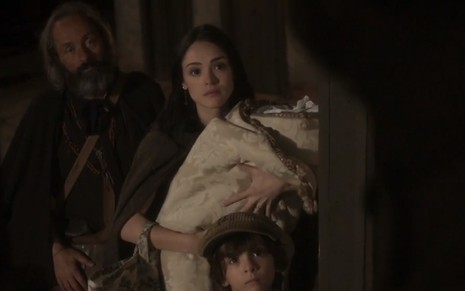 Anna (Isabelle Drummond) com um bebê no colo ao lado de Olinto (Daniel Dantas) em cena de Novo Mundo