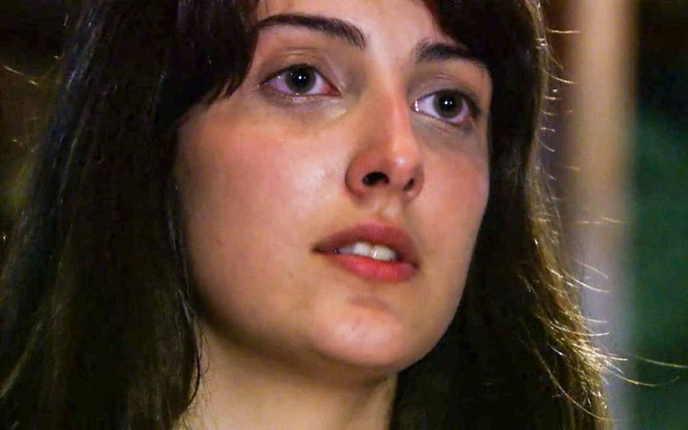 A atriz Clarice Falcão como Mariana em A Favorita; ela está olhando para frente com cara de sofrimento