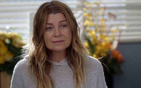 Ellen Pompeo está com expressão triste em cena de Grey's Anatomy; ela está com uma blusa e caracterizada como Meredith Grey
