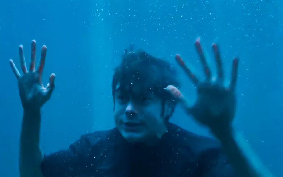 O ator Rafael Vitti como Davi em Além da Ilusão; ele está dentro de um tanque de água, com as mãos encostadas no vidro e cara de desesperado