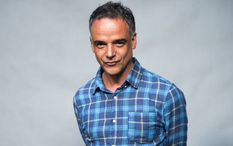 Ângelo Antônio posa paa a foto de camisa xadrez azul, sorrindo