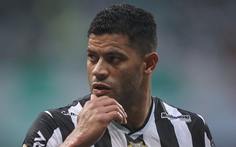 Hulk, do Atlético Mineiro, com mão no queixo, veste uniforme listrado em branco e preto durante jogo