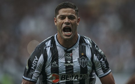 Jogador Hulk, do Atlético Mineiro, veste uniforme branco com listras pretas e comemora gol feito em partida
