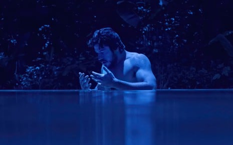 Marco Pigossi dentro de um rio em cena da segunda temporada da série Cidade Invisível
