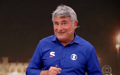 Cleber Machado com uma blusa azul e sorriso na transmissão da Copa