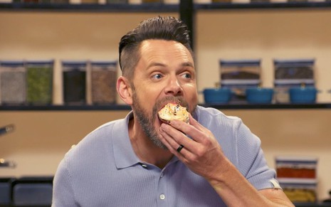 Joel McHale abre a boca para engolir cupcake inteiro em cena do reality Celebrity Beef
