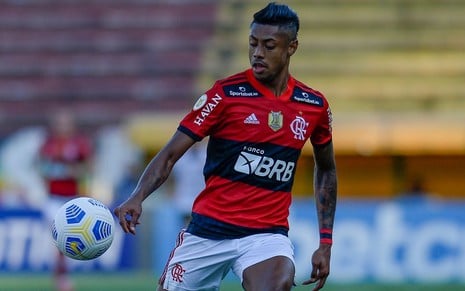 Foto do jogador de futebol Bruno Henrique, do Flamengo, chutando uma bola em campo durante uma partida