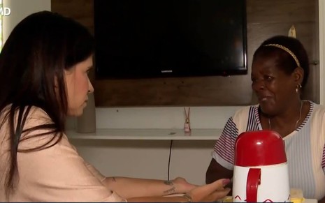 Imagem de Adriana entrevistando Malena; a jornalista veste camiseta bege; Madalena veste camiseta branca com detalhes na cor azul