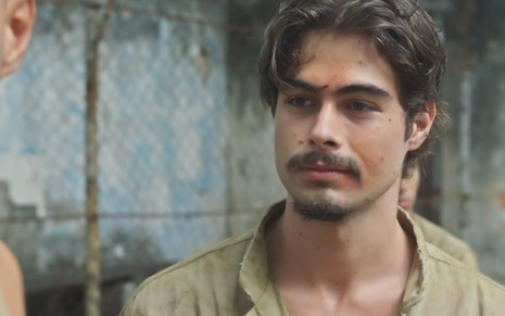O ator Rafael Vitti, com roupas de prisioneiro e alguns machucados no rosto, como o Davi em cena de Além da Ilusão
