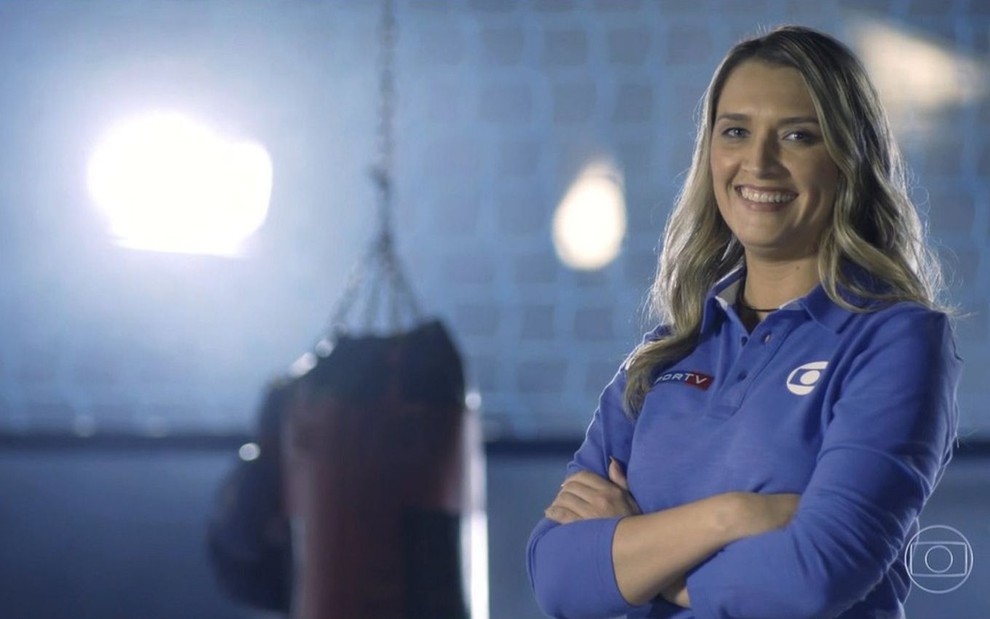 Ana Thaís Matos, comentarista da Globo, aparece sorrindo com uma camisa azul e um fundo que lembra uma academia de box na chamada para os Jogos Olímpicos na Globo