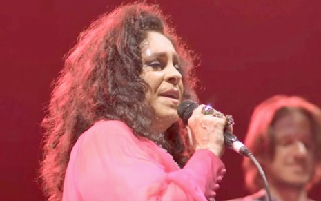 A cantora Gal Costa está de rosa com microfone na mão em imagem exibida em homenagem do Fantástico
