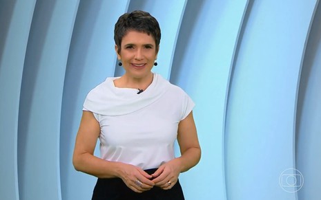 Com blusa branca e sorriso, Sandra Annenberg está no cenário virtual do Globo Repórter