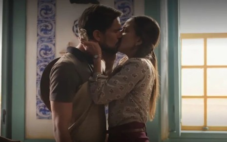 Julia Mendes, caracterizada como Anita, agarra Matteus Cardoso, o Joel, pelo pescoço em cena de Mar do Sertão; ela beija o rapaz com fervor