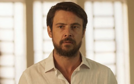 Sergio Guizé usa uma camisa social branca, barba bem aparada e cabelo penteado em cena de Mar do Sertão