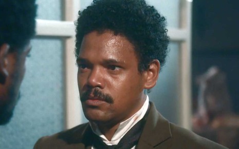 O ator Michel Gomes com expressão séria, suado, como o Samuel em cena de Nos Tempos do Imperador