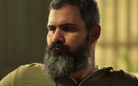 Juliano Cazarré, caracterizado como Alcides, tem a expressão pensativa em cena de Pantanal