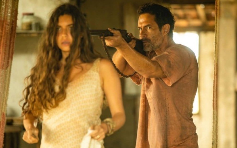 Juma (Alanis Guillen) está com a arma de Solano (Rafael Sieg) apontada na cabeça na novela Pantanal