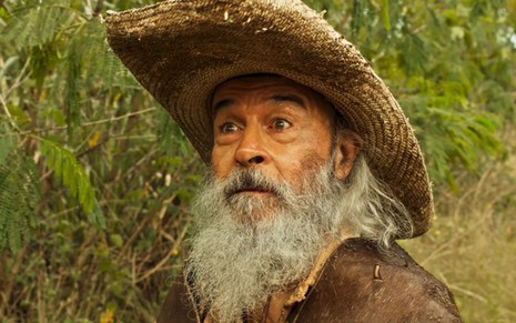 O ator Osmar Prado como Velho do Rio em Pantanal; ele está de chapéu, virado para o lado, olhando fixamente com cara de surpreso