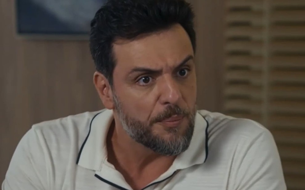 Rodrigo Lombardi usa uma camiseta polo branca em cena de Travessia; ele tem o semblante furioso e transtornado