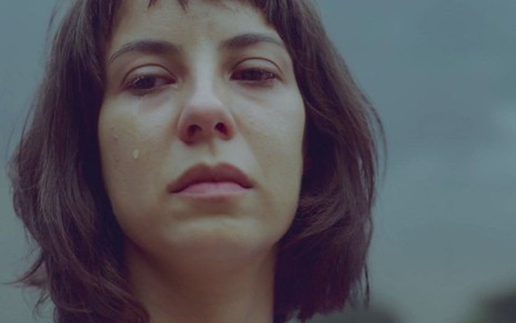 Com lágrima escolhendo pelo rosto, Andréia Horta, caracterizada como Lara, olha para além do quadro em gravação de cena de Um Lugar ao Sol