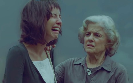 Andréia Horta e Marieta Severo em cena de Um Lugar Ao Sol: caracterizada como Lara, atriz chora e Marieta a olha enquanto coloca sua mão no ombro esquerdo da parceira de cena